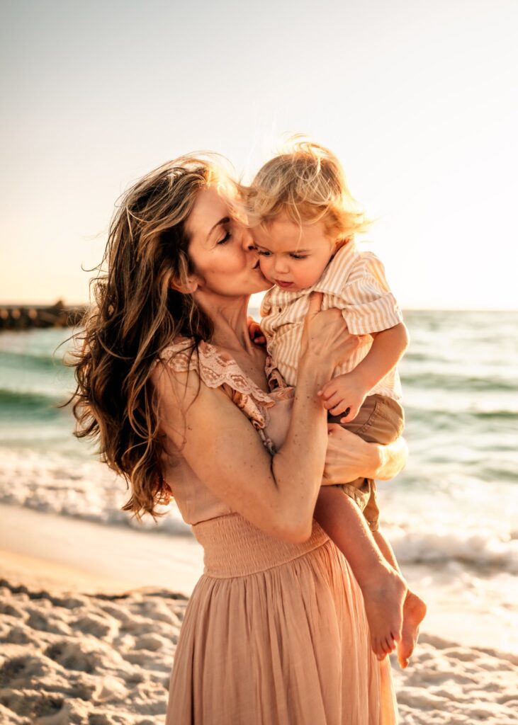 mom-holding-and-kissing-baby-on-the-beach