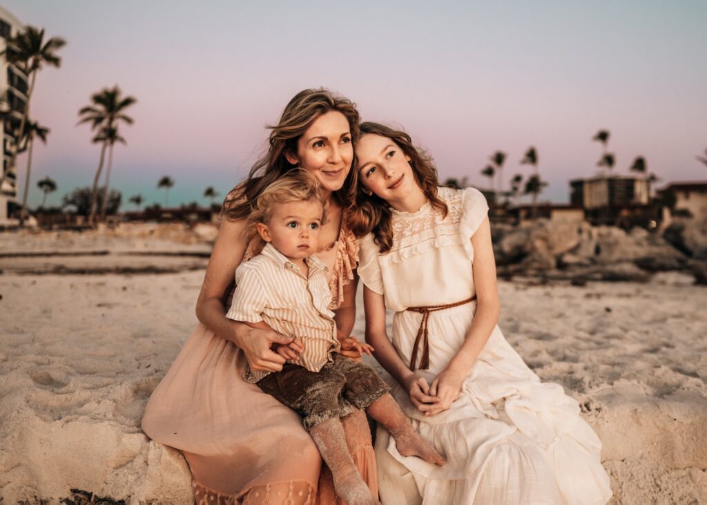 mother-sitting-on-beach-with-kids-watching-sunset
