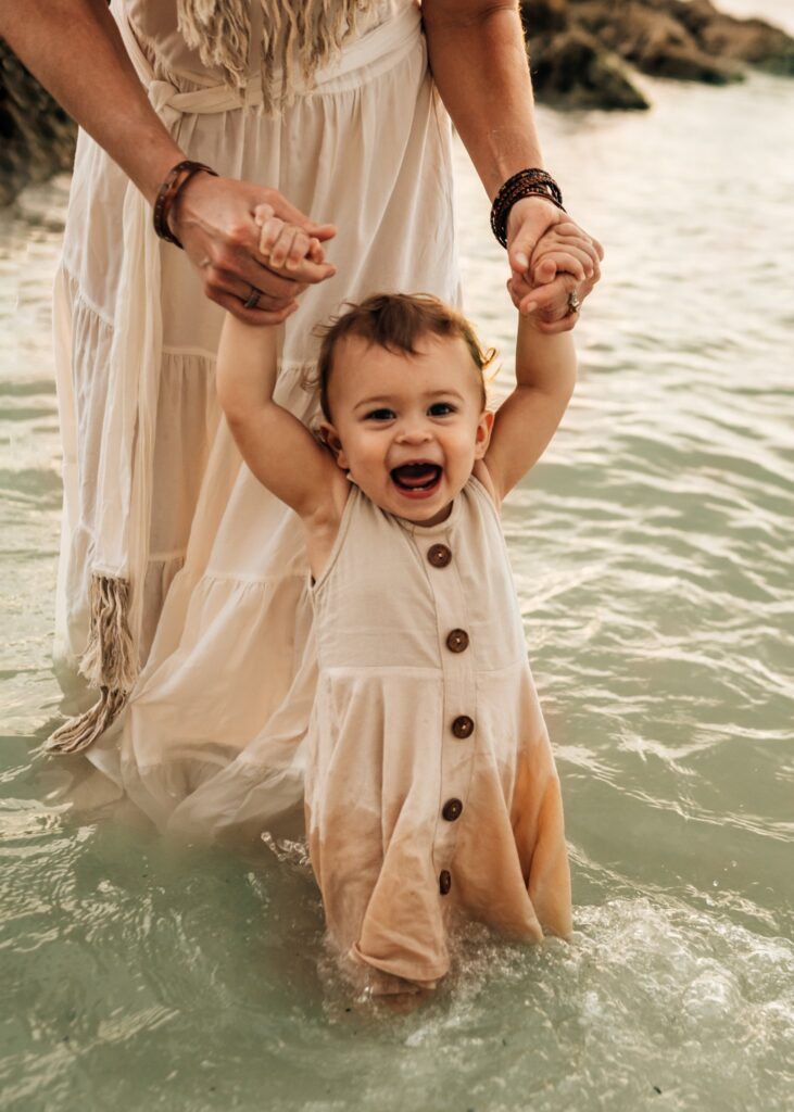 baby-laughing-in-water-holding-moms-hands